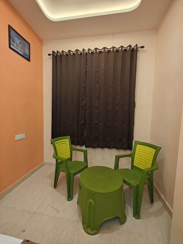 A small room with two green plastic chairs and a round table. - HOTEL PINK CITY (Sikar)