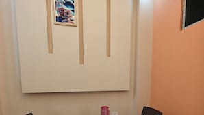 A room with a table and two chairs, a pink water bottle, and a framed picture on the wall. - HOTEL PINK CITY (Sikar)
