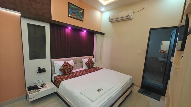 A hotel room with a bed, bedside table, air conditioning unit, and a bathroom visible through an open door. - HOTEL PINK CITY (Sikar)