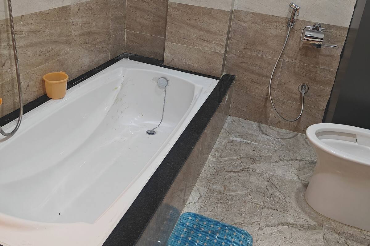 A bathroom with a bathtub, a toilet, and a shower area.
