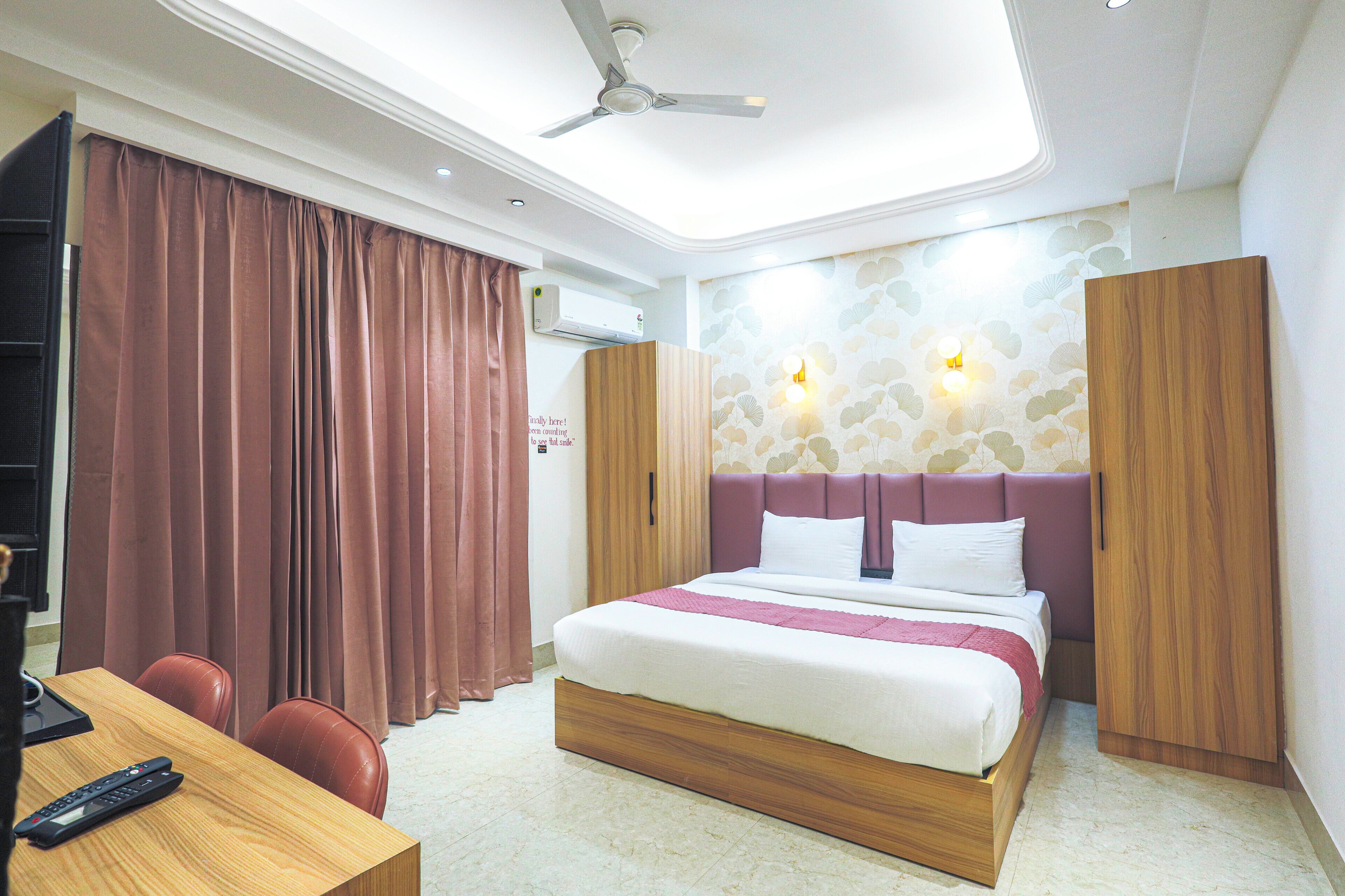 Une chambre d’hôtel équipée d’un lit, d’un bureau, d’une chaise, d’un ventilateur de plafond et d’une armoire.