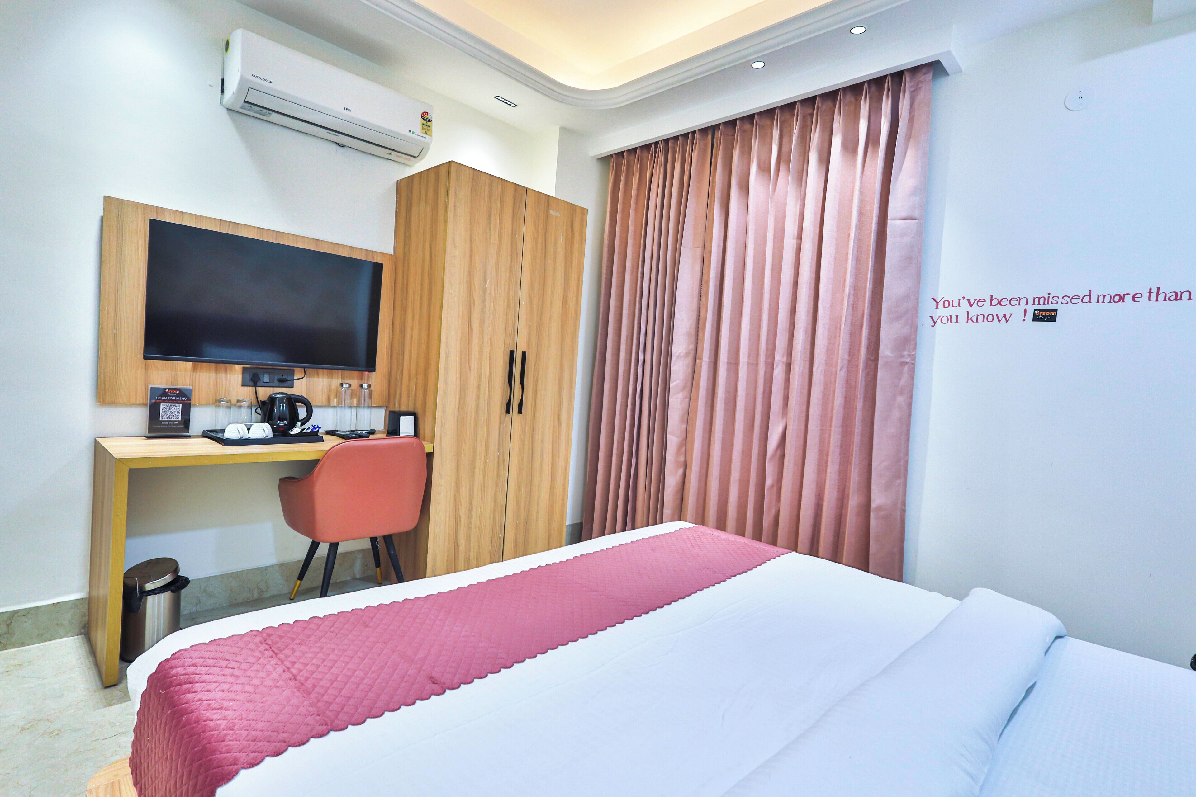 Ein Hotelzimmer mit Bett, Schreibtisch mit Stuhl, Klimaanlage und einem Fenster mit Vorhängen.