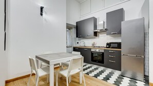 Una cocina moderna con armarios blancos, un refrigerador de acero inoxidable y una mesa de comedor con sillas.