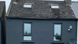 Ein zweistöckiges Gebäude mit dunkler Fassade, einer zentralen Tür mit Messinggriff und mehreren Fenstern.