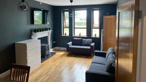 Ein modernes Wohnzimmer mit Kamin, einer Couch, einem Esstisch und einem Fernseher.