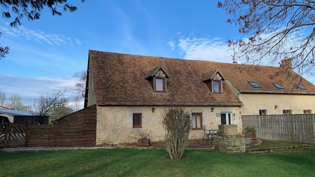 A two-story stone house with a sloped roof, a wooden fence, and a well-maintained lawn. - Country house close to town (Champfleur)