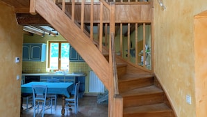 A wooden staircase leading to a kitchen area with blue cabinets and a dining table set. - Country house close to town (Champfleur)