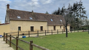 A rustic stone building with a tiled roof, a wooden fence, and a grassy yard. - Country house close to town (Champfleur)
