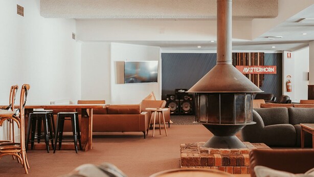 A cozy lounge area with a central wood-burning stove, comfortable seating, and a modern design.