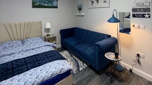 A bedroom with a bed, a blue sofa, a world map, and a lamp.