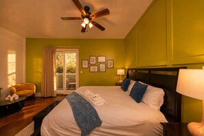 A bedroom with a bed, a ceiling fan, a window with curtains, and a chair.