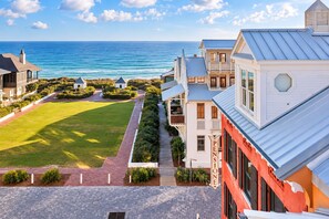A coastal property with a view of the ocean, a paved pathway, and a well-maintained lawn.