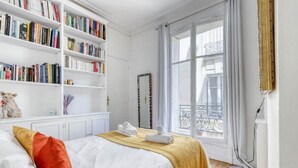 Un dormitorio con una cama grande, una estantería, una ventana con vistas y un espejo.
