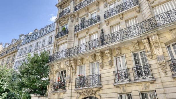 Un edificio de varios pisos con balcones ornamentados y detalles arquitectónicos clásicos.