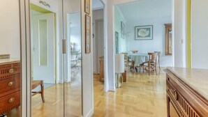 Een ruime hal met houten vloeren, een eetgedeelte met een tafel en stoelen, en een spiegel die de ruimte weerspiegelt.