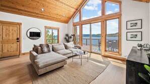 A spacious living room with a large window, wooden ceiling, and a cozy sofa.