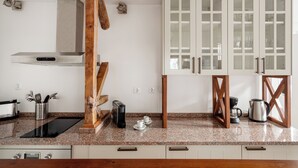 Een keuken met een roestvrijstalen afzuigkap, houten balken, witte kasten met glazen deuren en een granieten aanrecht.