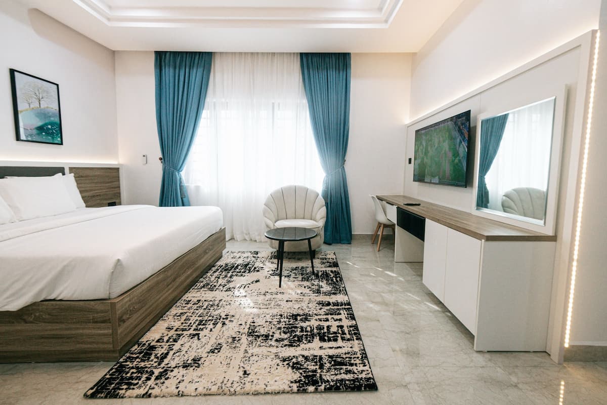 A modern bedroom with a bed, a desk, and a TV.