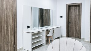 A modern room with a white desk, a large mirror, a chair, and a wardrobe. - 5blu Residence  (Abuja)