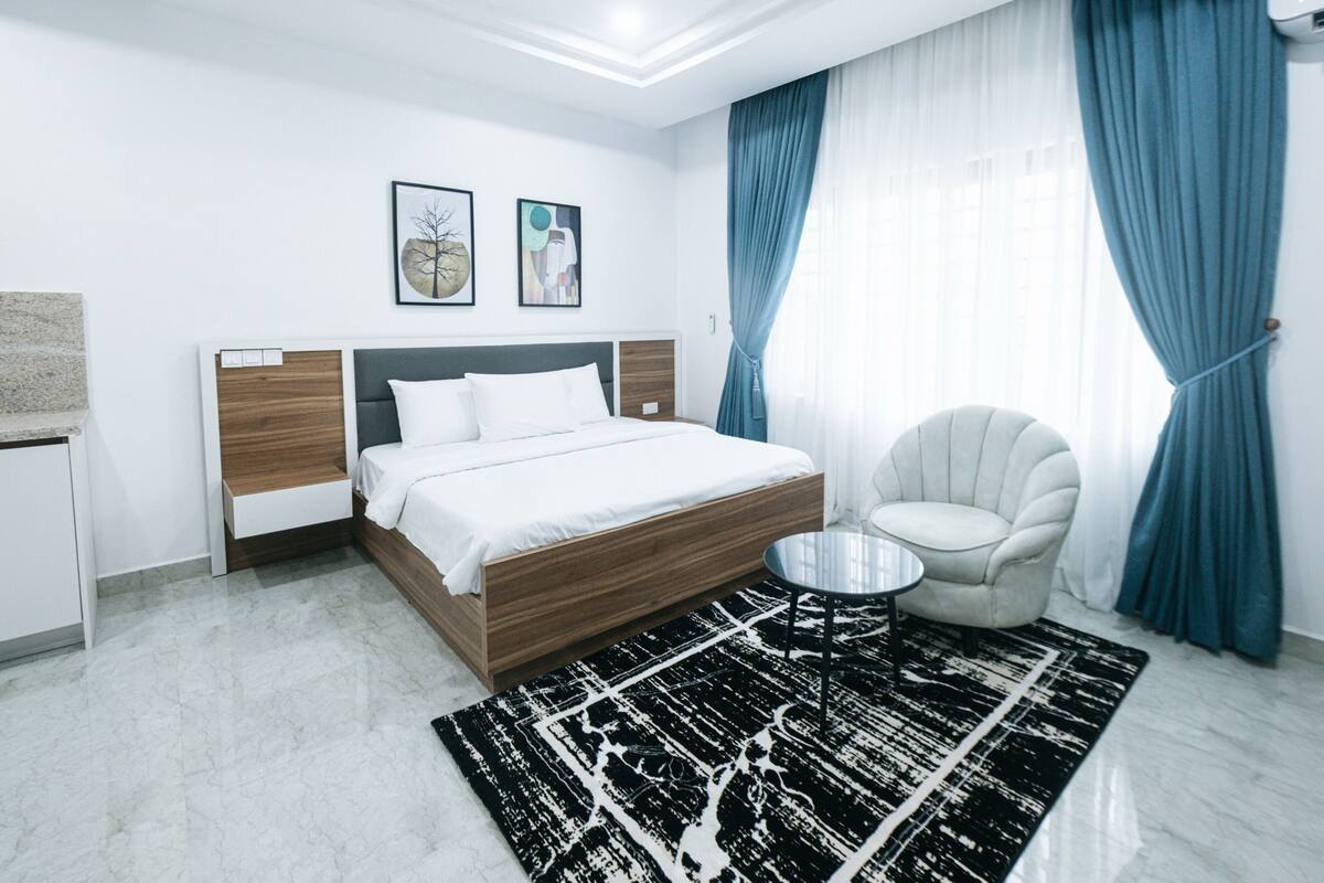 A modern bedroom with a wooden bed, a round table, and a chair.