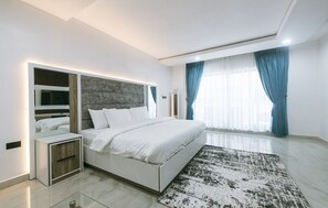 A modern bedroom with a large bed, bedside tables, and a built-in wardrobe.