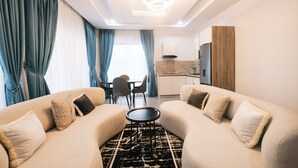 A modern living room with a sofa set, a dining table, and a kitchen area. - 5blu Residence  (Abuja)