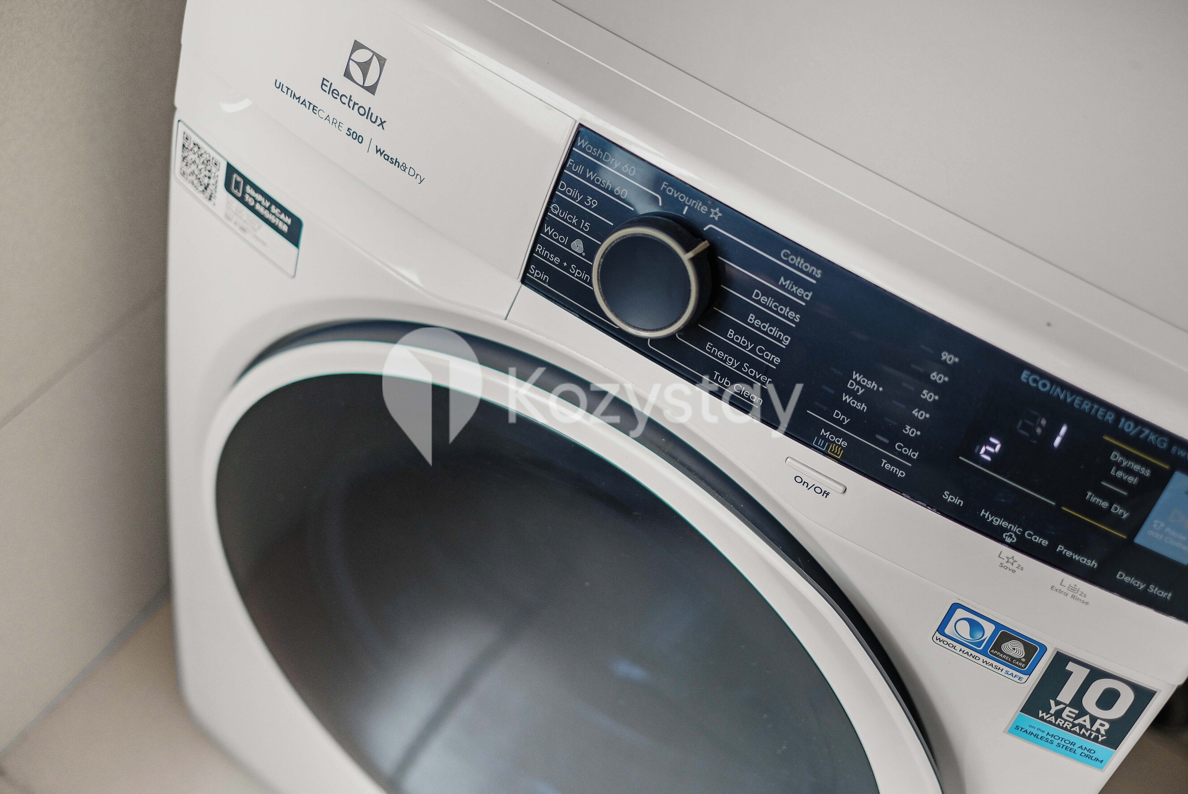 A front view of a washing machine with a digital display, control panel, and a 10-year warranty sticker.