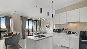 A modern kitchen with a central island, white cabinetry, and a large window offering a city view.