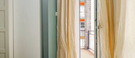Habitación de hotel con cama, armario y puerta corrediza de vidrio que da a un balcón.