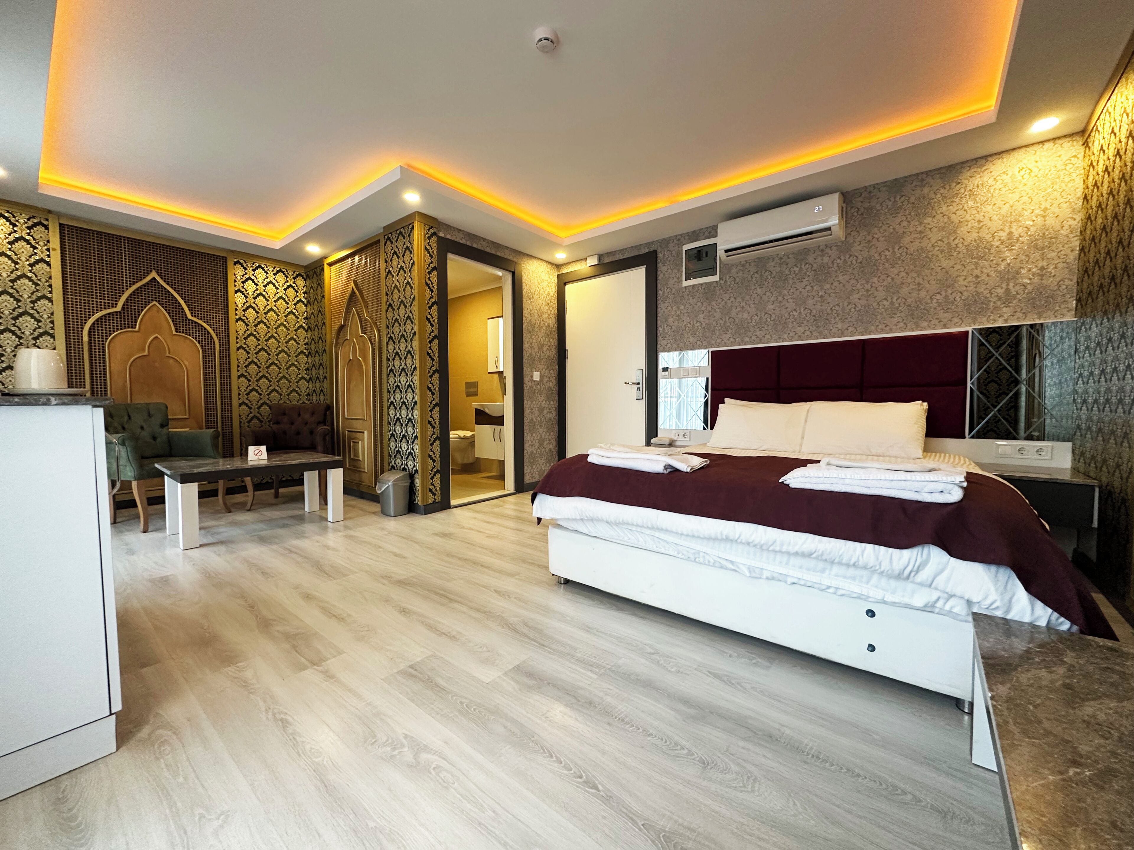 Una habitación de hotel moderna con una cama grande, zona de estar y baño a la vista a través de una puerta abierta.