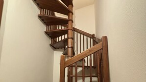 A wooden spiral staircase with a handrail and a landing area. - Window To The Tower (Pisa)