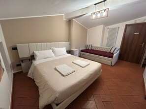 A bedroom with a large bed, a sofa, a nightstand, and a door. - Window To The Tower (Pisa)