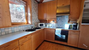 A compact kitchen with wooden cabinets, a microwave, a toaster, and a dishwasher.