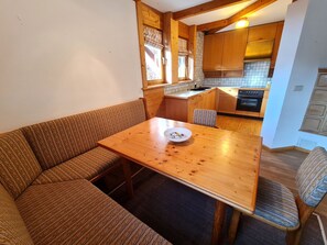 Une cuisine chaleureuse avec des meubles de rangement en bois, une table à manger et un four encastré.
