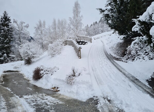 A snow-covered road with a bridge and trees.