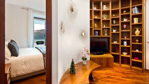 A bedroom with a bed, a TV, and a wooden cabinet with shelves. - The Lake View (Castel Gandolfo)