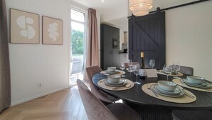 A dining area with a round table set for six, a dark wooden wall, and a sliding barn door.
