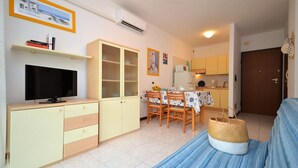 A compact living space with a TV, dining table, chairs, and a sofa. - Beachfront stay with terrace (Bibione)
