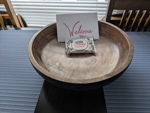 A wooden bowl on a table with a 'Welcome' card and a packet of 'Big Spoon Roasters Cranberry Cashew' in it. - Walk to Duke & Dining • Charming Historic 2BR (Durham)