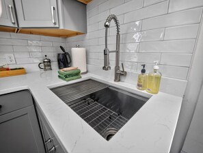 Een keuken met een roestvrijstalen spoelbak, een kraan en een betegelde spatwand.