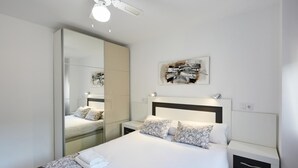 A modern bedroom with a large bed, bedside tables, a mirror, and a ceiling fan. - Superior Apartment, 3 min. to the beach (Benidorm)
