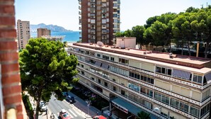 A multi-story building with balconies, a street view, and a clear sky. - Deluxe Apartment, 3 min from the beach (Benidorm)
