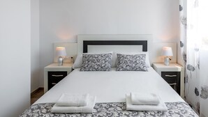 A neatly made bed with patterned pillows and two bedside lamps. - Penthouse with Sea View (Benidorm)