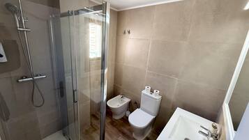 Une salle de bain moderne avec une douche à parois de verre, des toilettes et un lavabo.