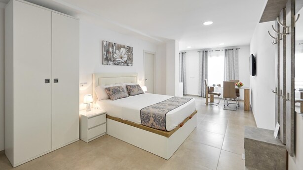 A modern bedroom with a large bed, bedside tables, a desk, and a chair. - Deluxe Studio Apartment 100 meters from the beach (Benidorm)