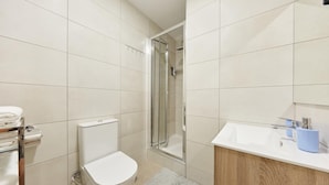 Een moderne badkamer met toilet, douche en wastafel.
