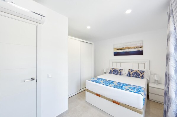 A bedroom with a bed, a nightstand, a painting, and a wardrobe.