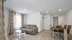 Ein modernes Wohnzimmer mit einer Couch, einem Glastisch und einem Essbereich mit Tisch und Stühlen.
