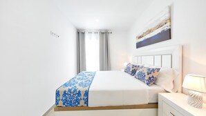 Een moderne slaapkamer met een bed, nachtkastje en een schilderij aan de muur.