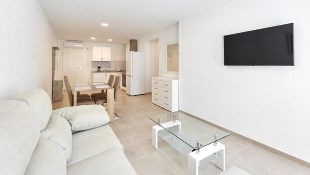 Een modern appartement met een woonkamer, eethoek en keuken.